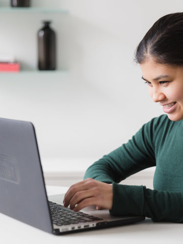 Woman using a laptop in a home office setting operating Finttabb Suite Software